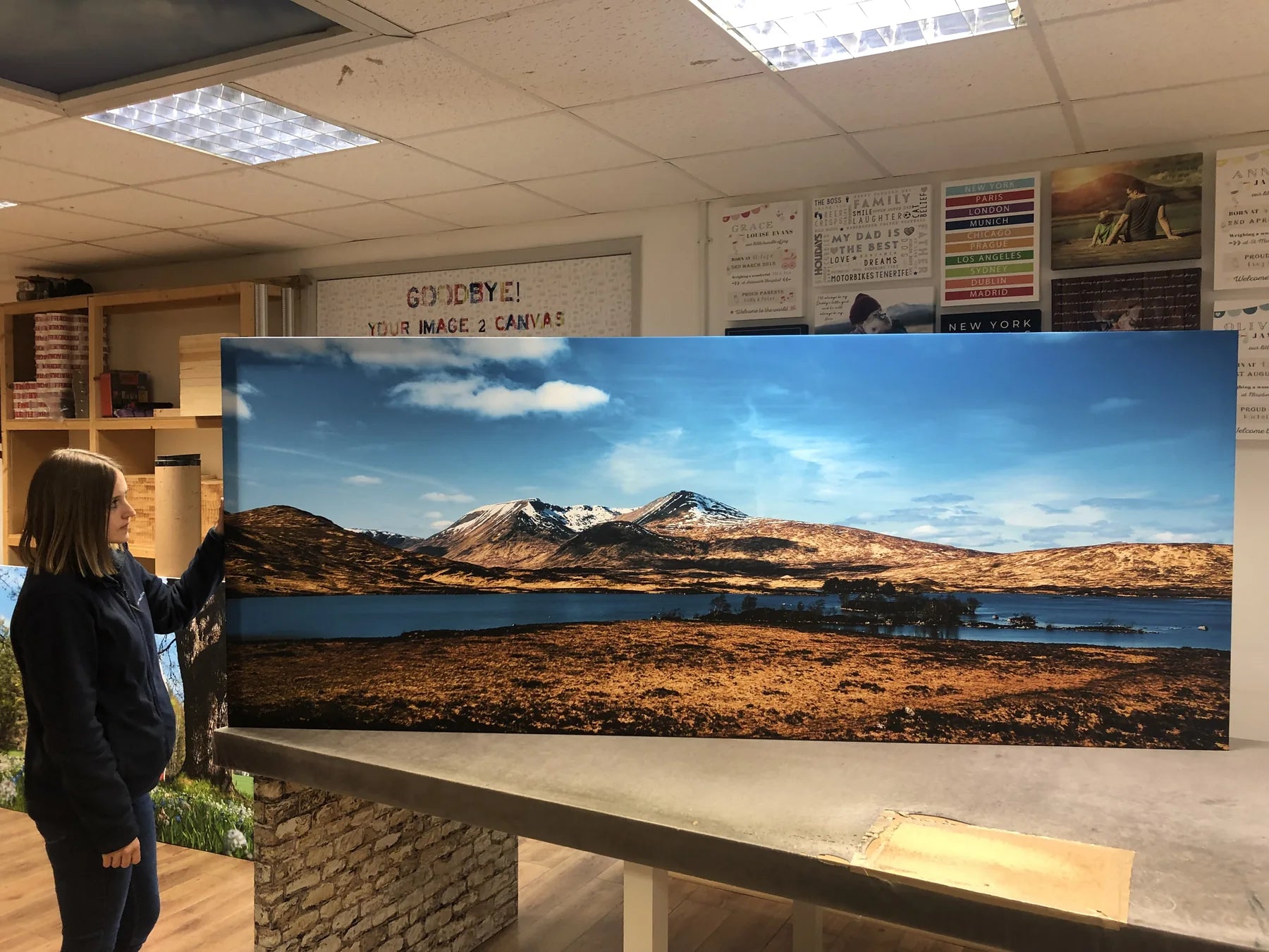 Two people checking a wide mountain panorama on a workshop bench