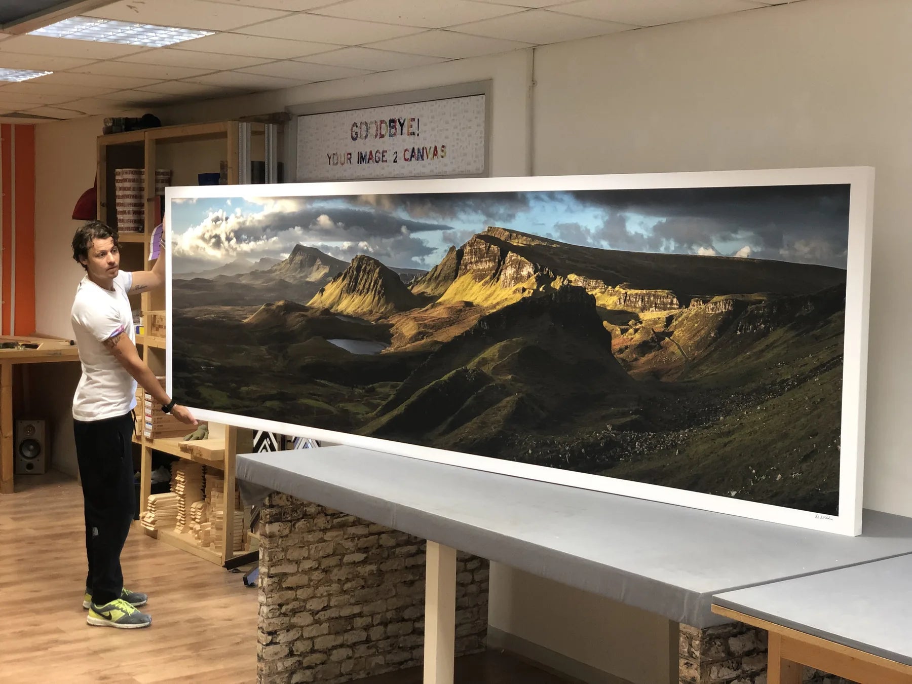 Two people presenting a very wide framed landscape print