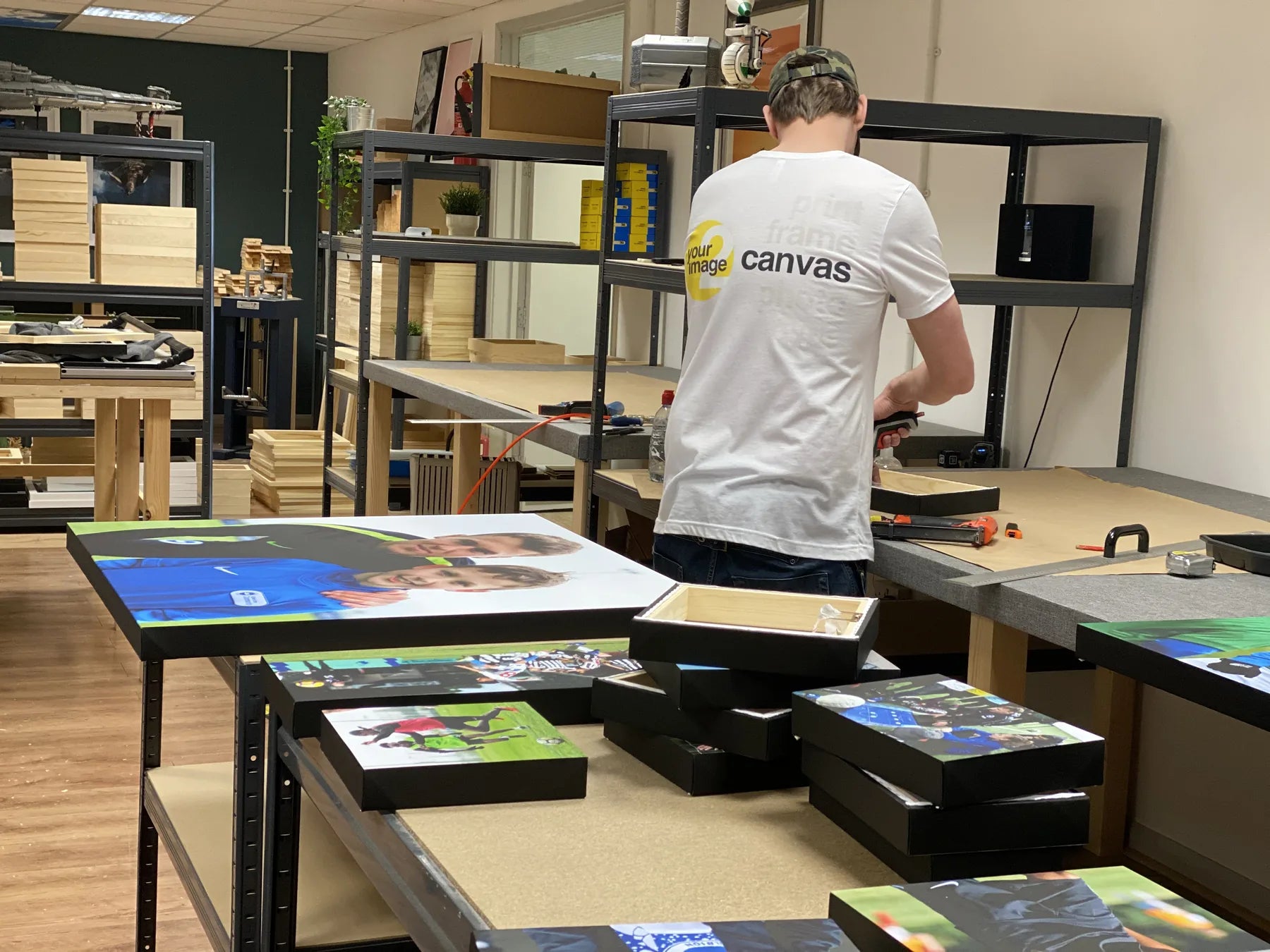 A printmaker working behind a table filled with finished canvases