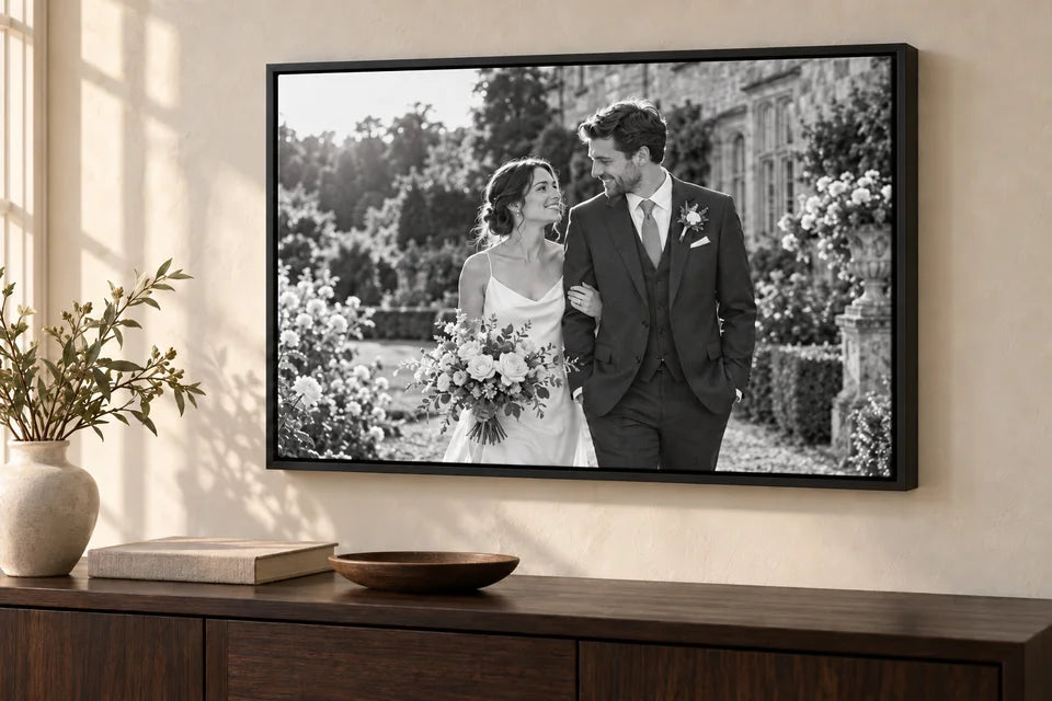 The same wedding photograph in black and white, inside the same black floating frame and room.