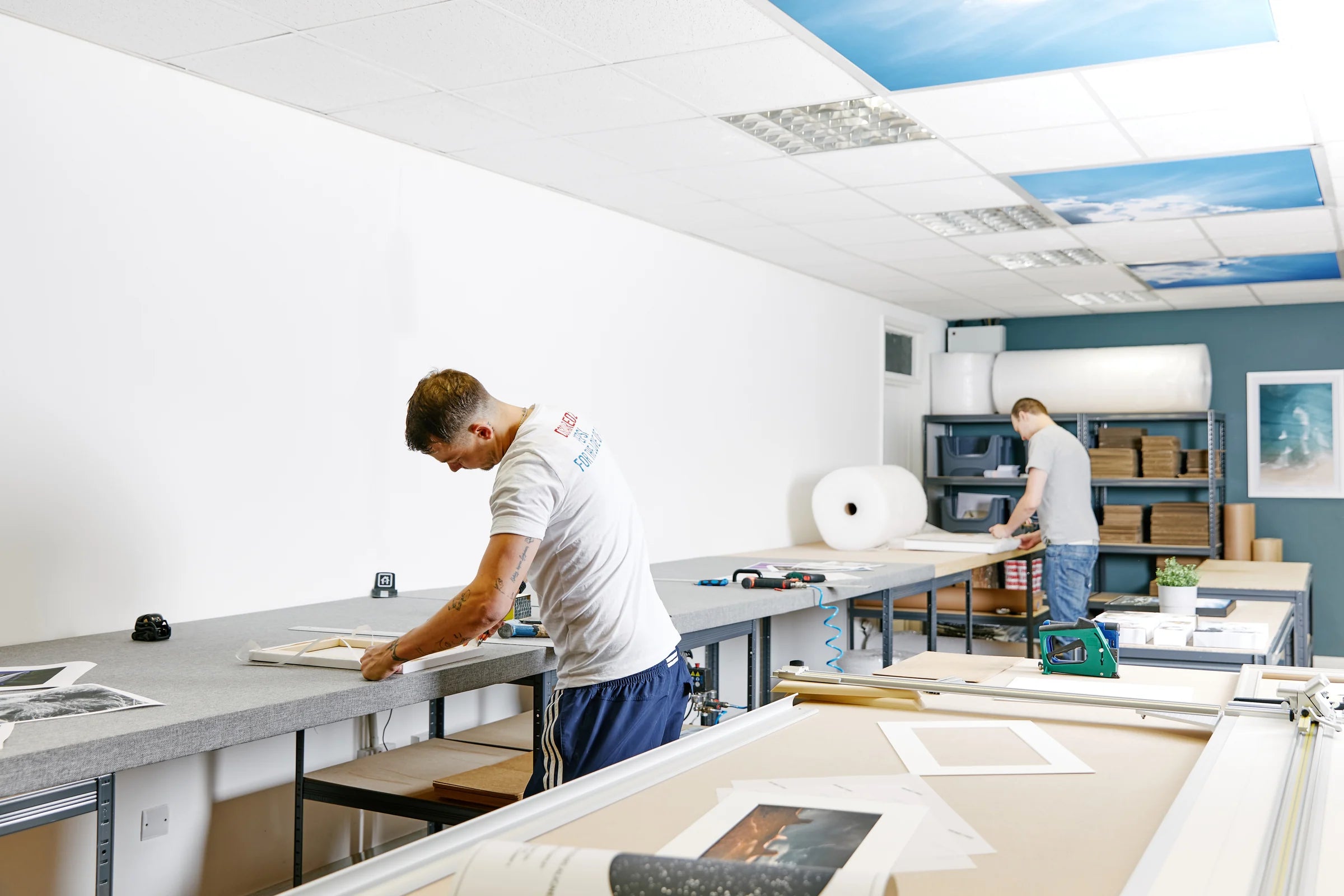 Two printmakers working at long finishing benches in the YI2C workshop