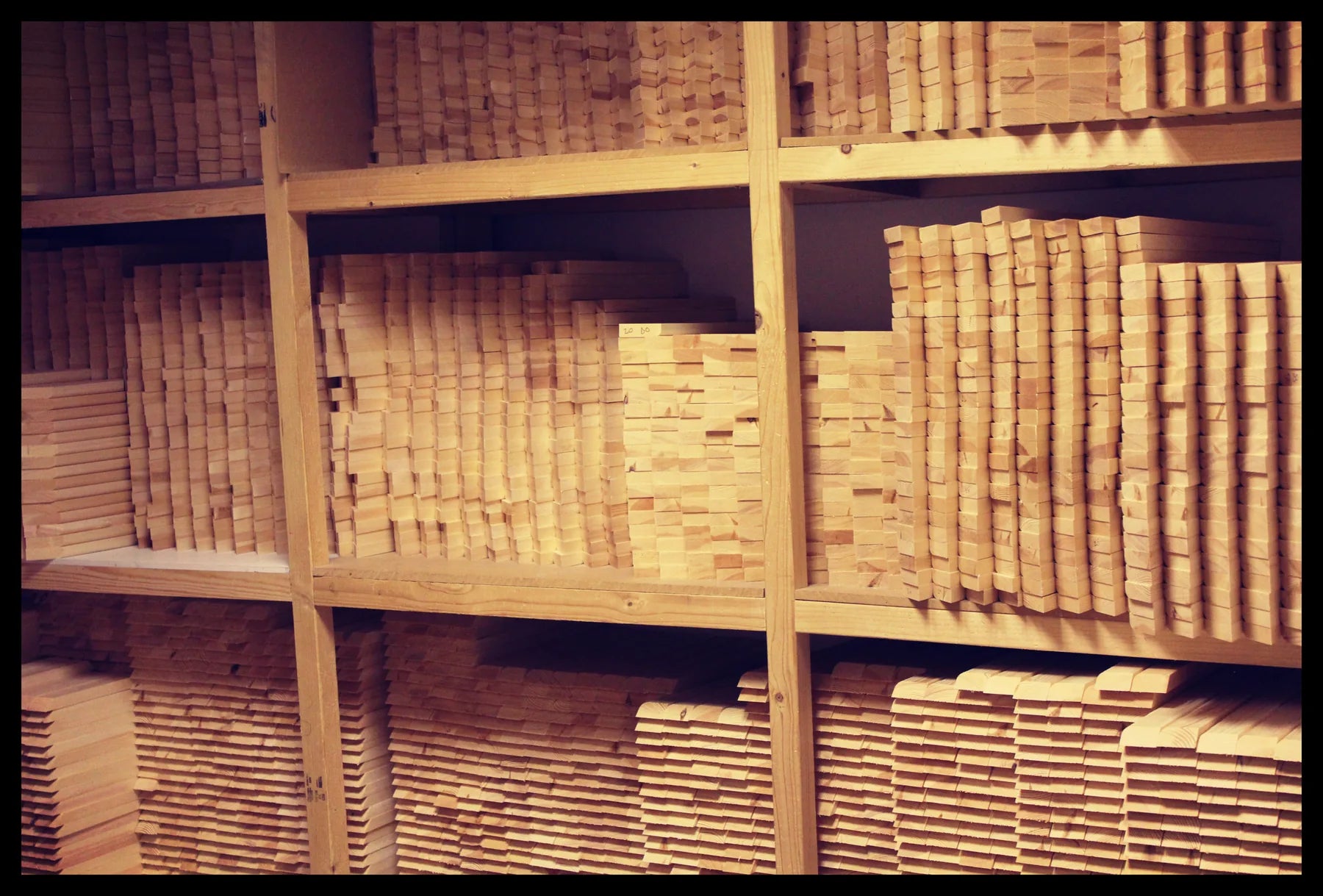 Shelves densely stacked with timber for canvas stretcher frames
