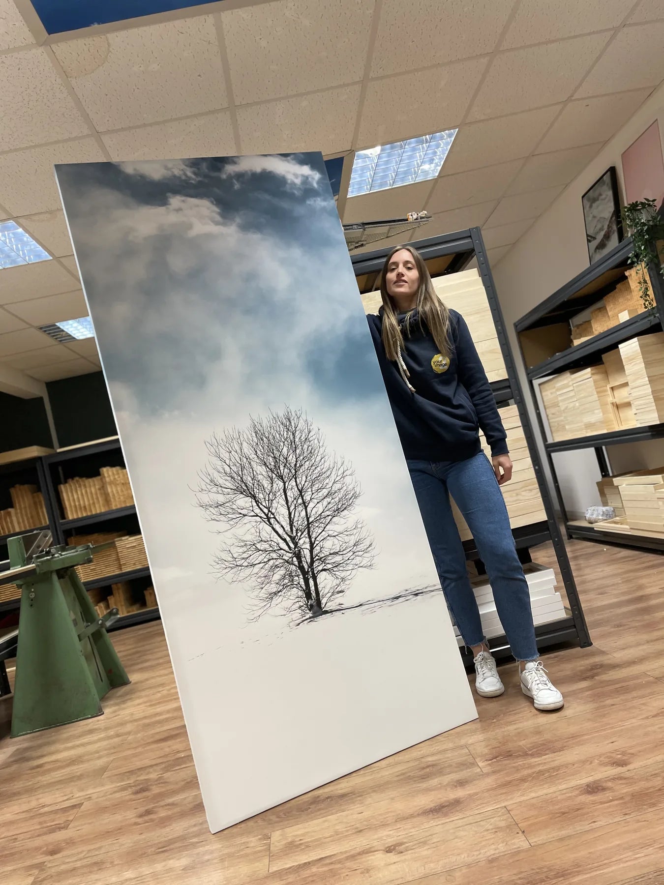 A person holding a tall monochrome tree canvas in the workshop