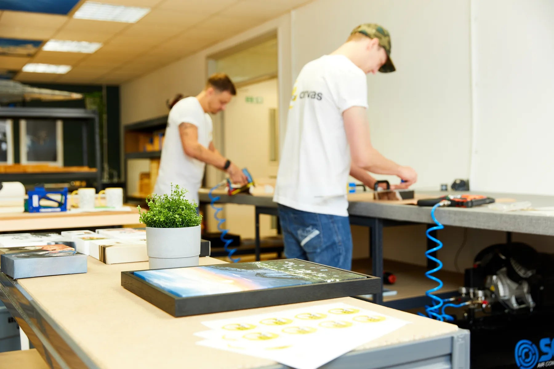 Two printmakers finishing canvases at neighbouring benches