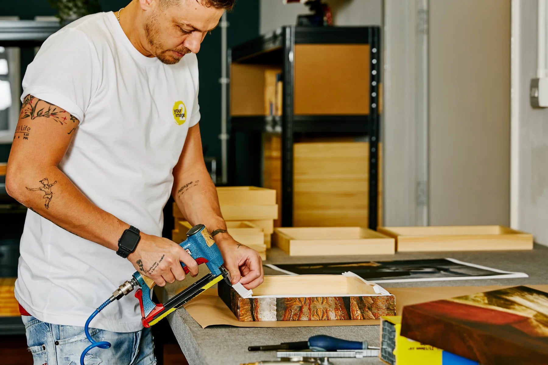 A printmaker stretching and stapling a photographic canvas by hand