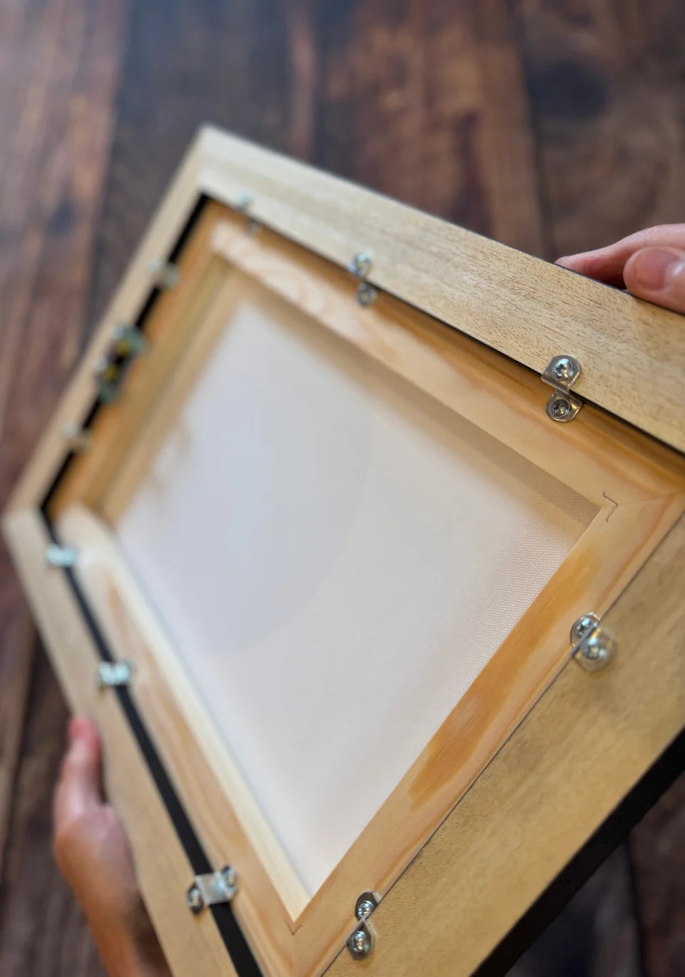 Close view of the wood and metal fixings on the back of a YI2C floating-frame canvas.