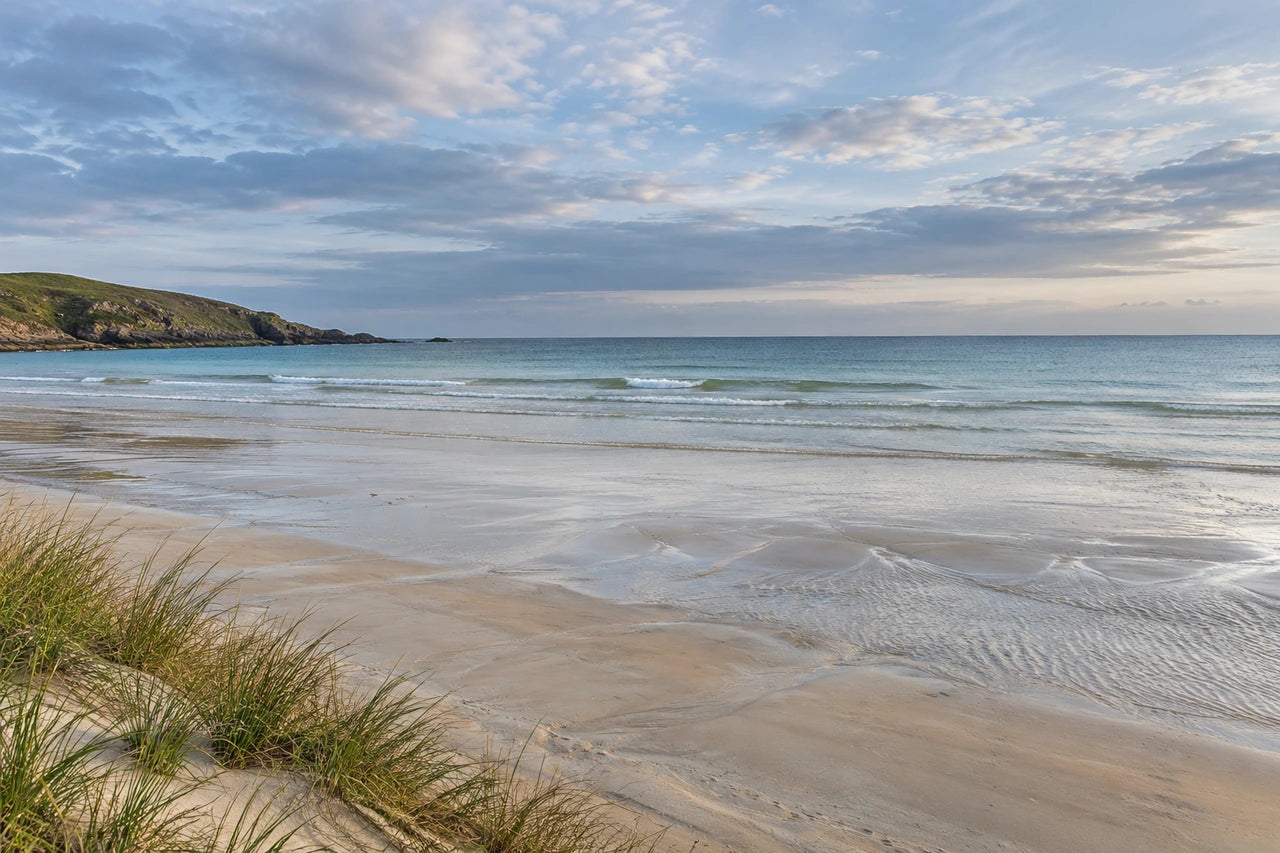 A fictional photographic-style coastal image with a left-hand headland, tidal sand and open water.