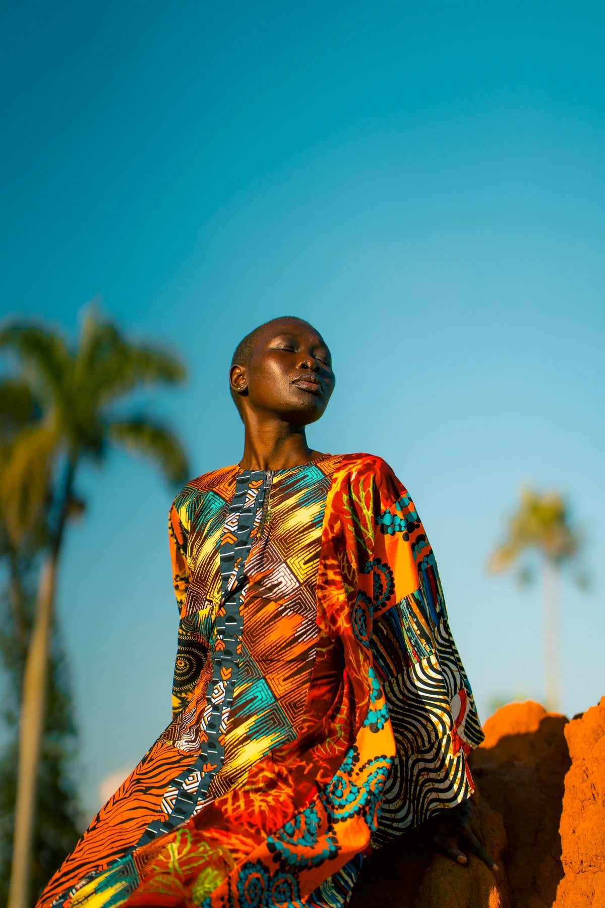 Orange outfit portrait beside a rough wall