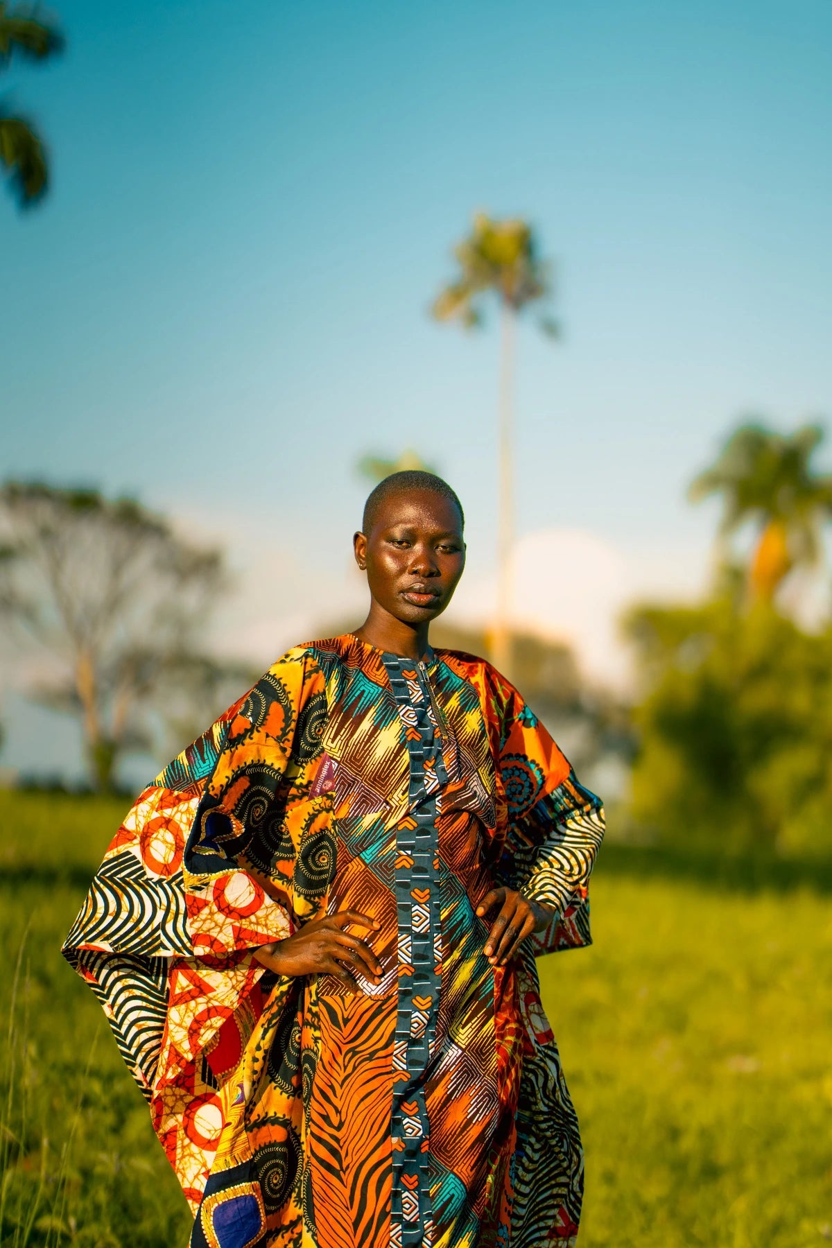 Portrait in an orange patterned outfit with hands on hips