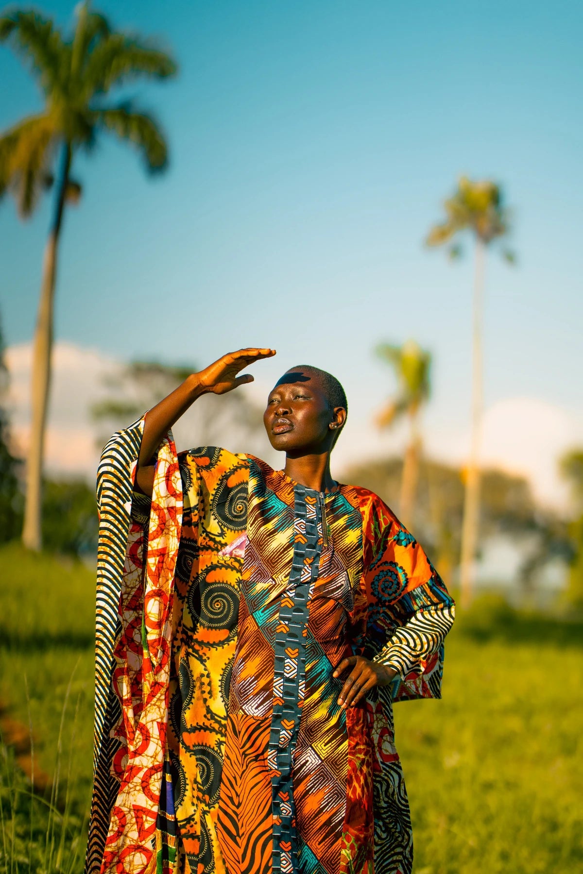Orange outfit portrait with one hand raised near forehead
