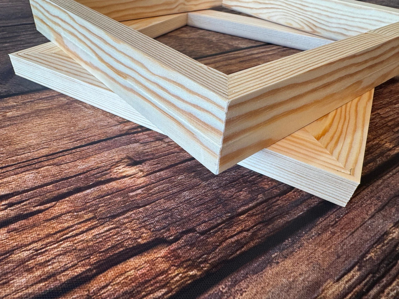 Stacked pine canvas stretcher frames showing the timber grain and mitred corners.
