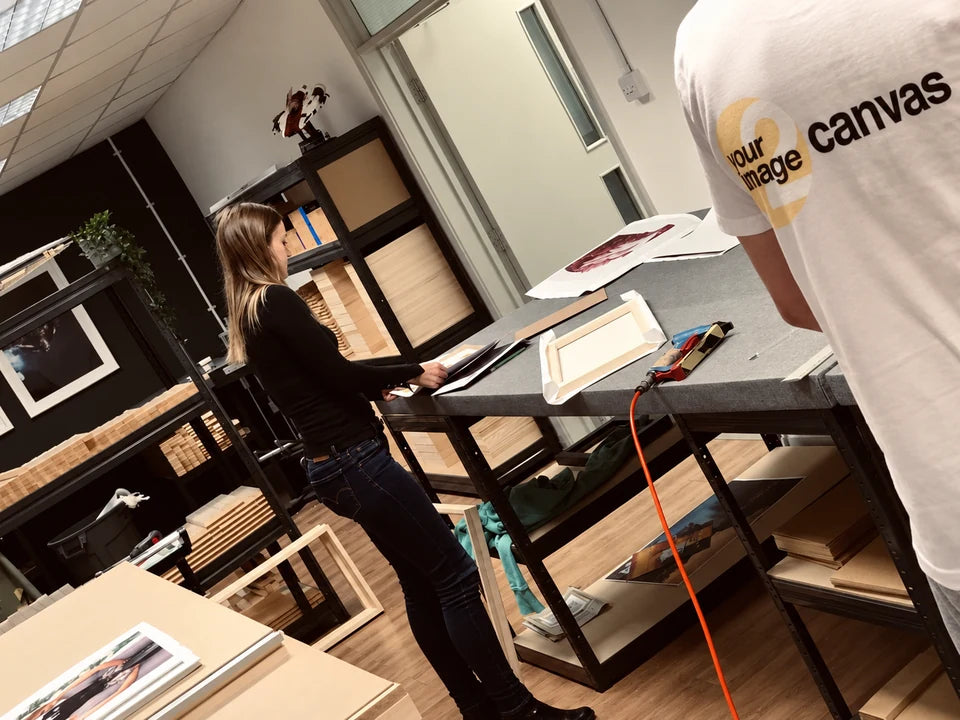 YI2C team members preparing a canvas at the framing bench, with a timber frame and stretching tools