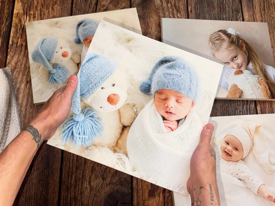 Hands holding a baby photo canvas above other finished prints