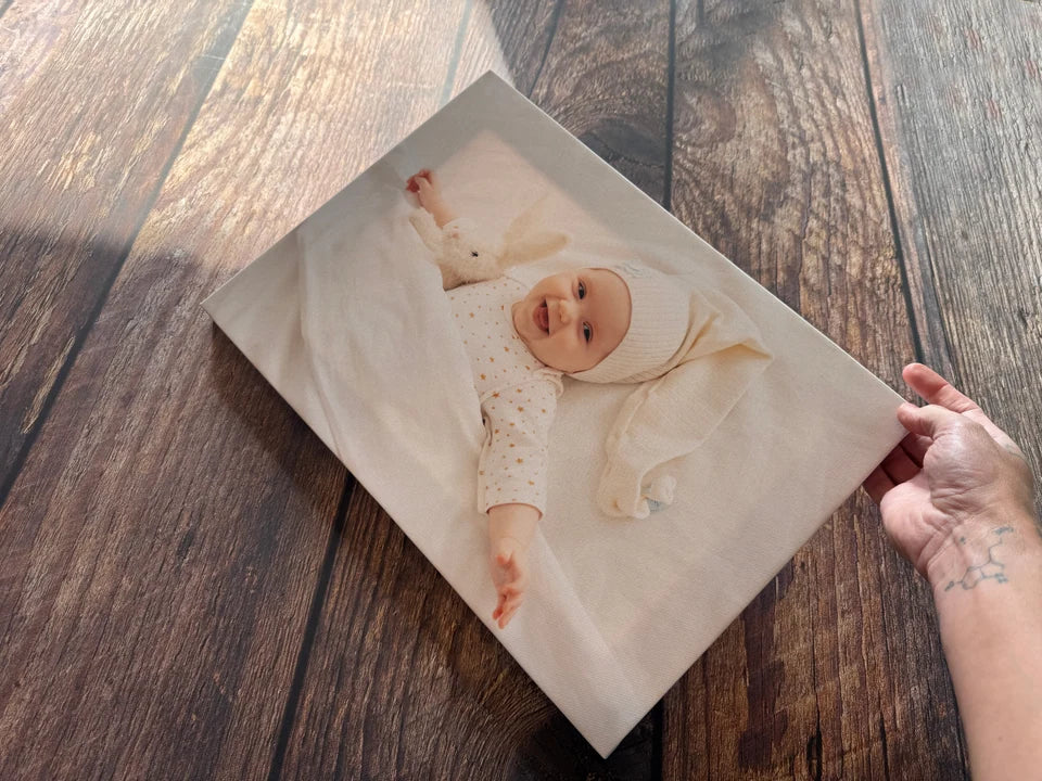 A baby photo canvas held in light across the workshop worktop