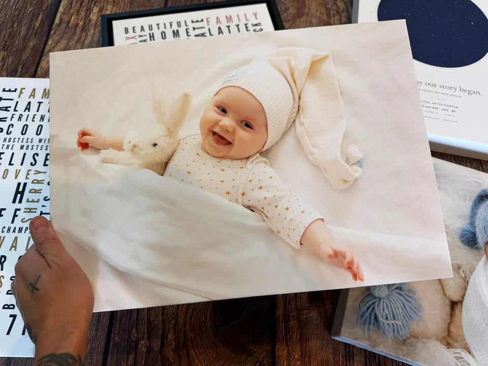 A baby photo canvas held above Word Art and Star Map prints