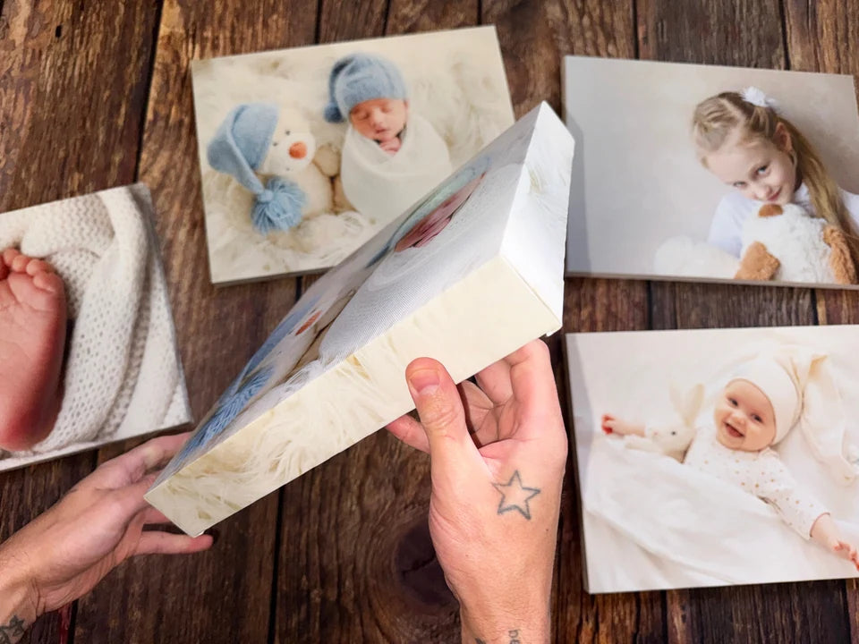 A canvas held side-on above a collection of finished photo canvases