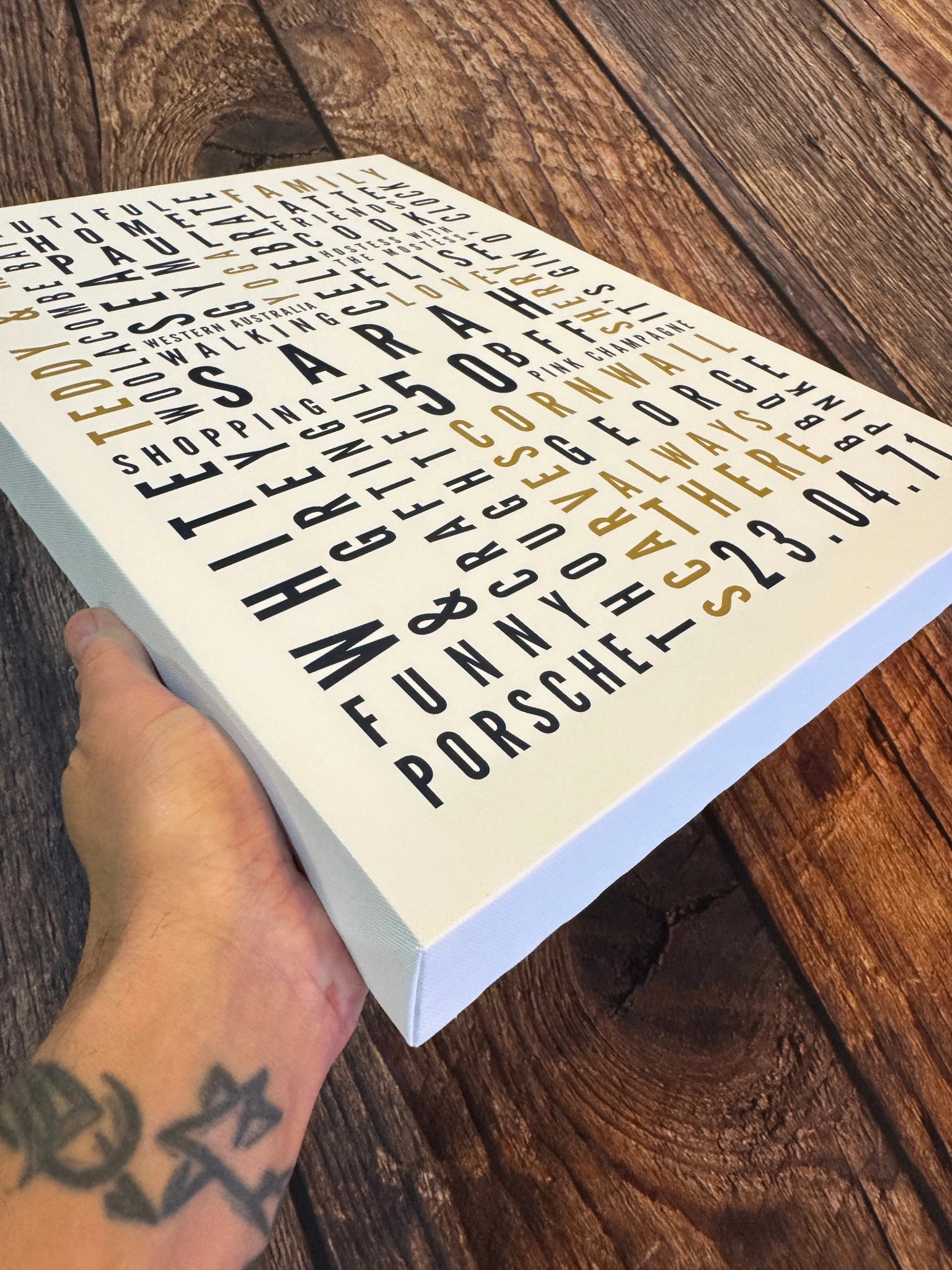 A chunky personalised Word Art canvas held at an angle to show its depth and wrapped corner.