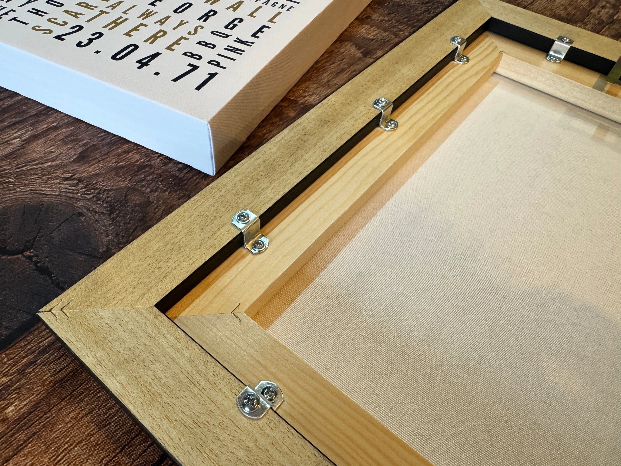 The back of a wooden floating frame, showing the canvas stretcher and metal fixings.
