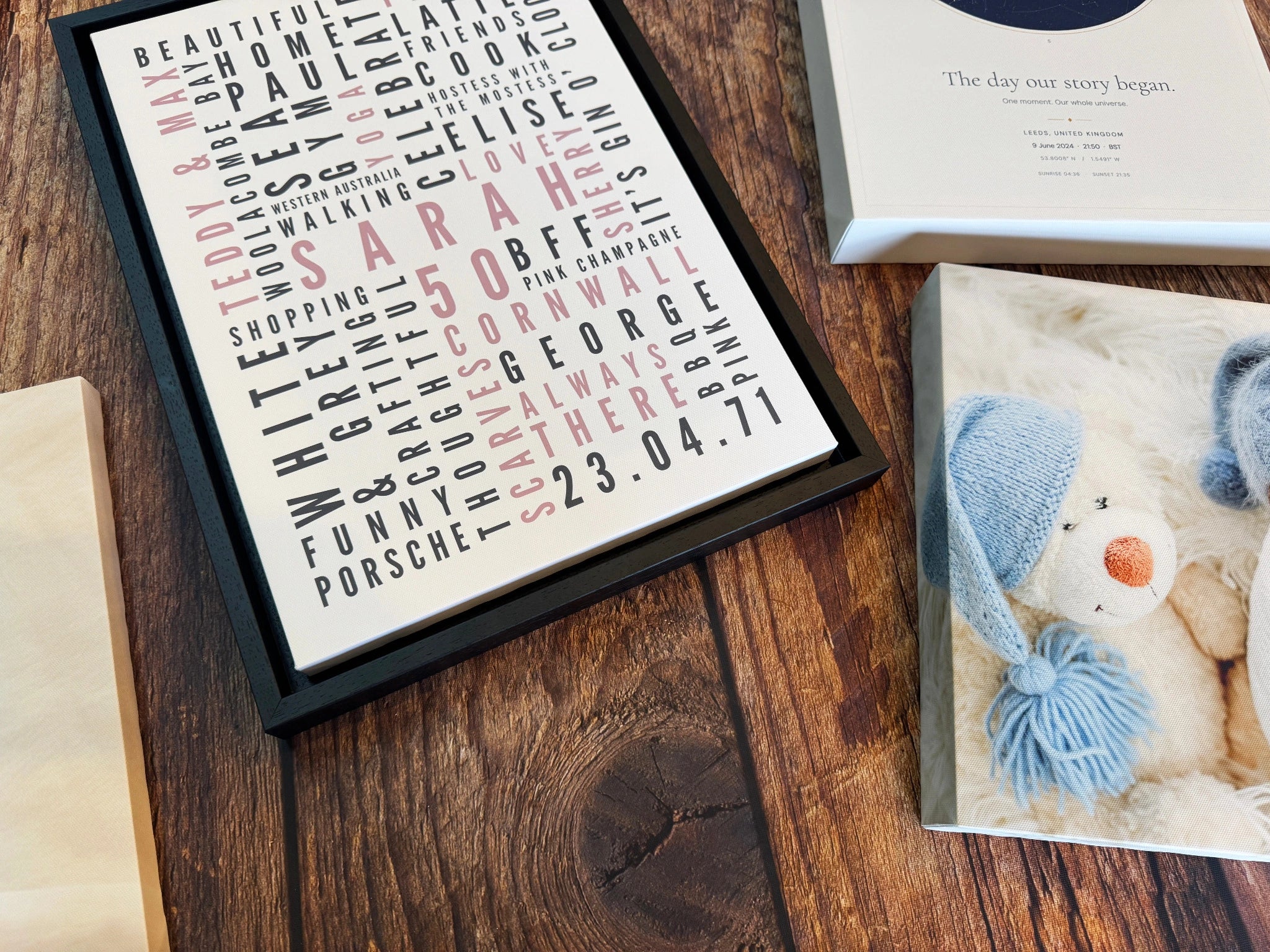 A finished personalised Word Art canvas in a black floating frame beside other prints on the worktop.