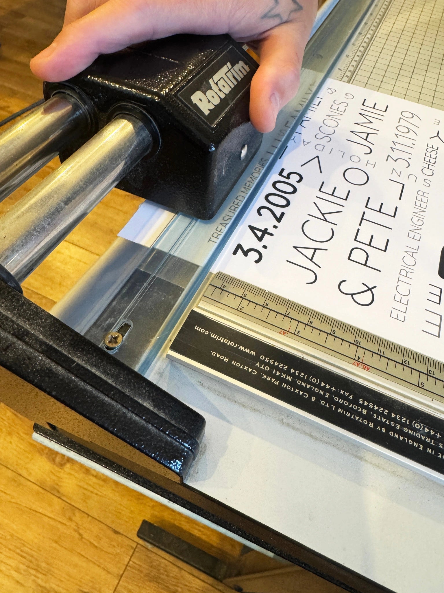 A close view of hands and a rotary trimmer cutting a personalised Word Art poster to size.