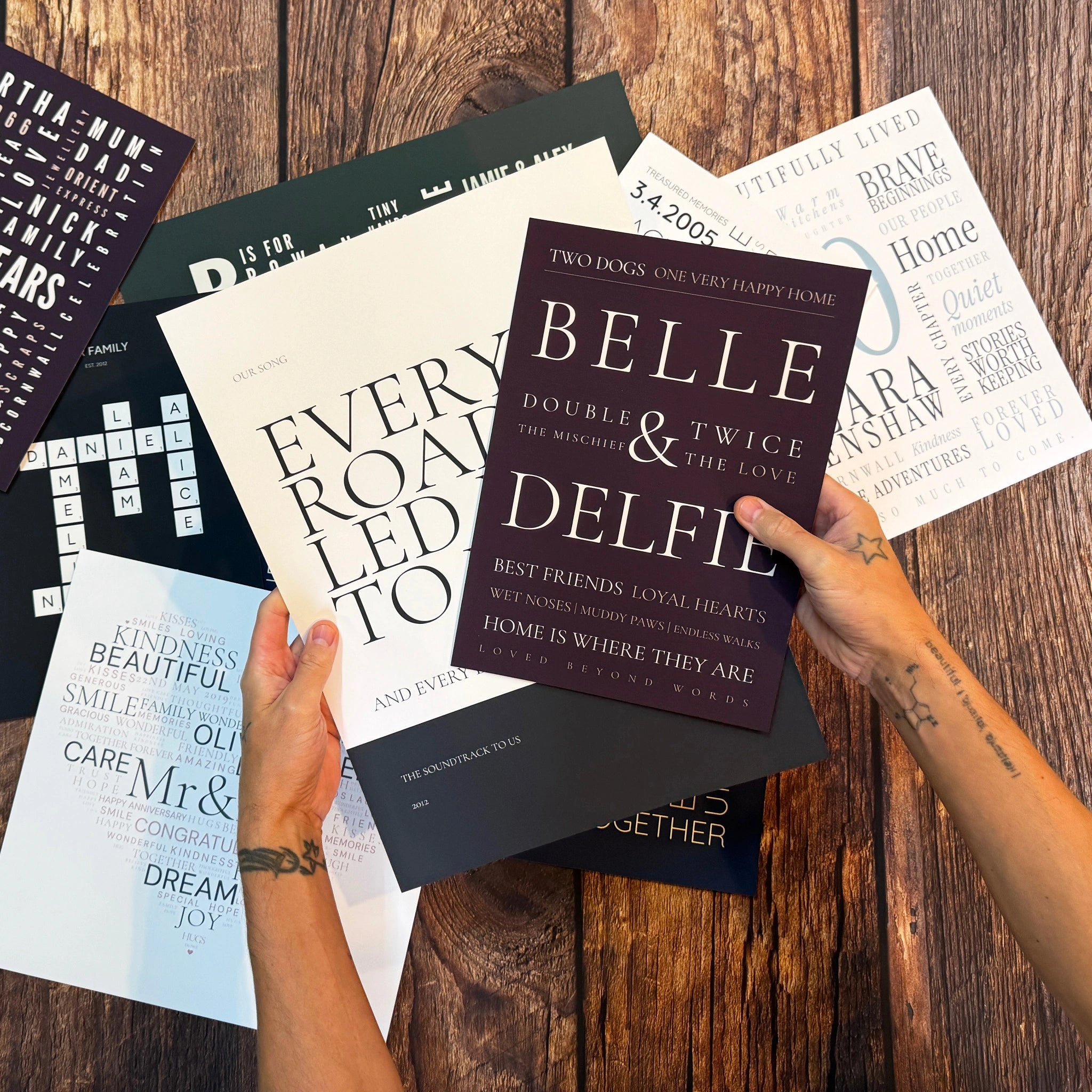 A Belle and Delfie Two of a Kind Word Art poster held above a selection of finished prints.