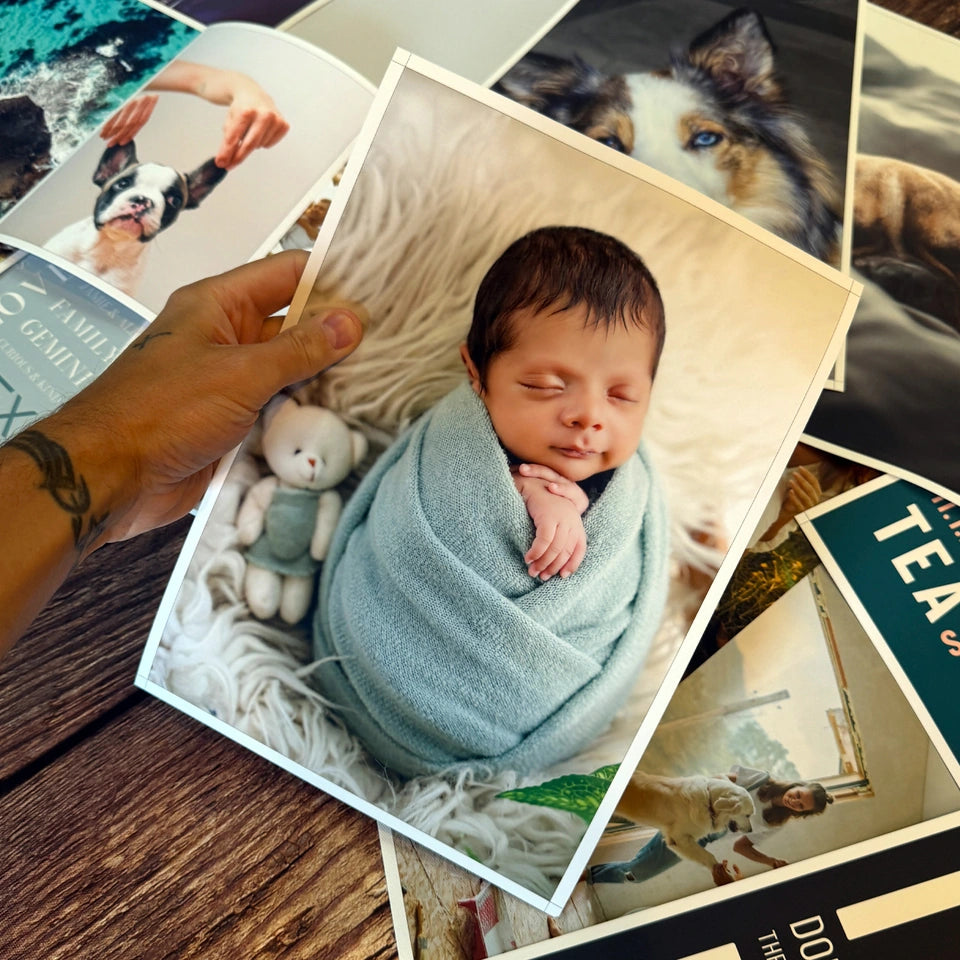 A baby photo poster held above a collection of paper prints