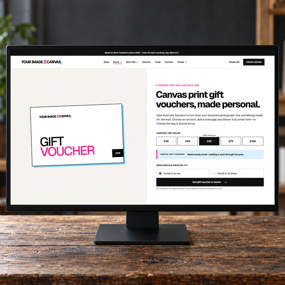 A monitor on a wooden table displaying the Your Image 2 Canvas digital gift voucher page