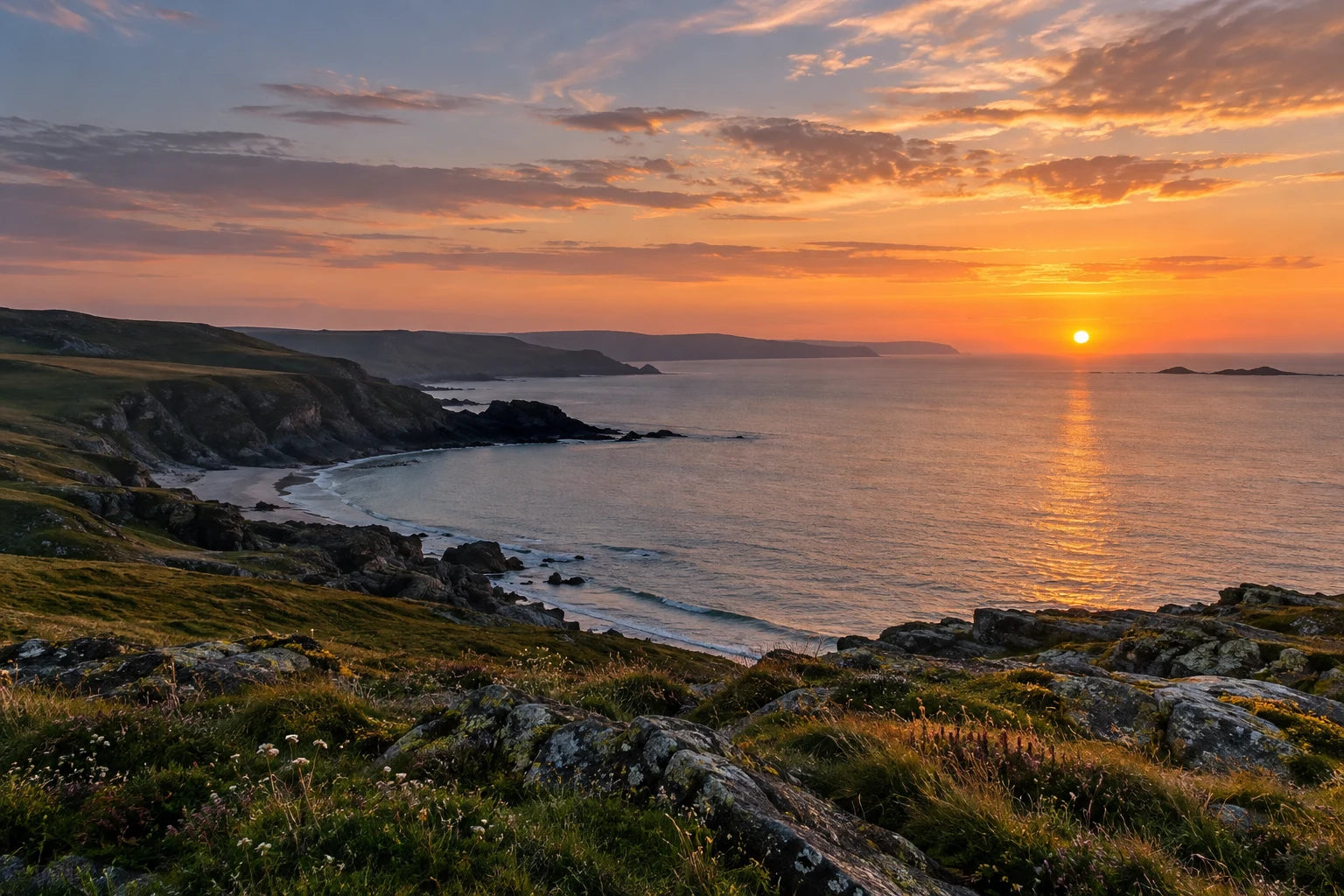 Photographic illustration of sunset over a coastal bay, with foreground rocks and warm light reflected on the sea.