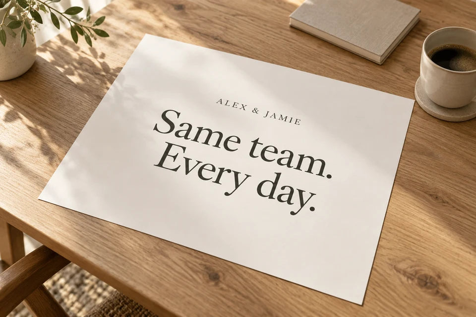 An unframed Word Art paper print reading Same team. Every day. on an oak table.