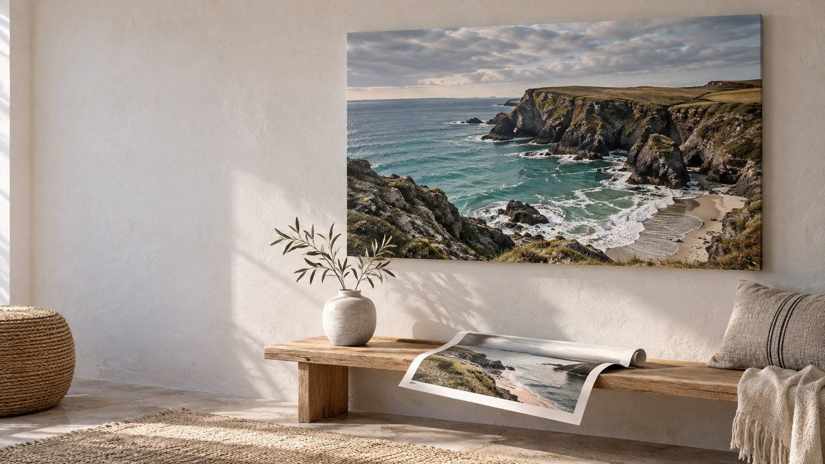 A large coastal photo canvas and an unframed paper print displayed above a bench in a light room.
