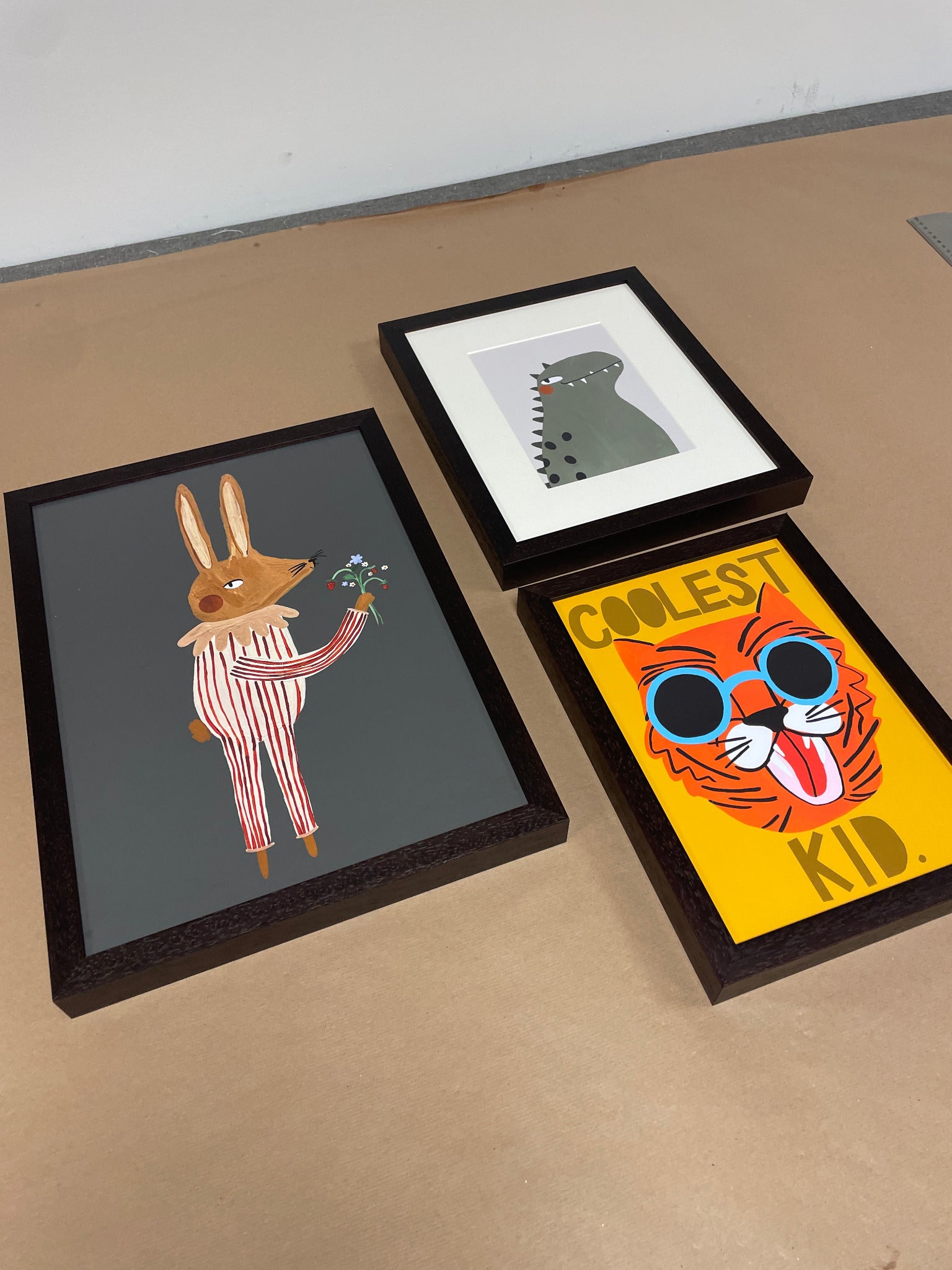 Three colourful illustrated prints in dark frames