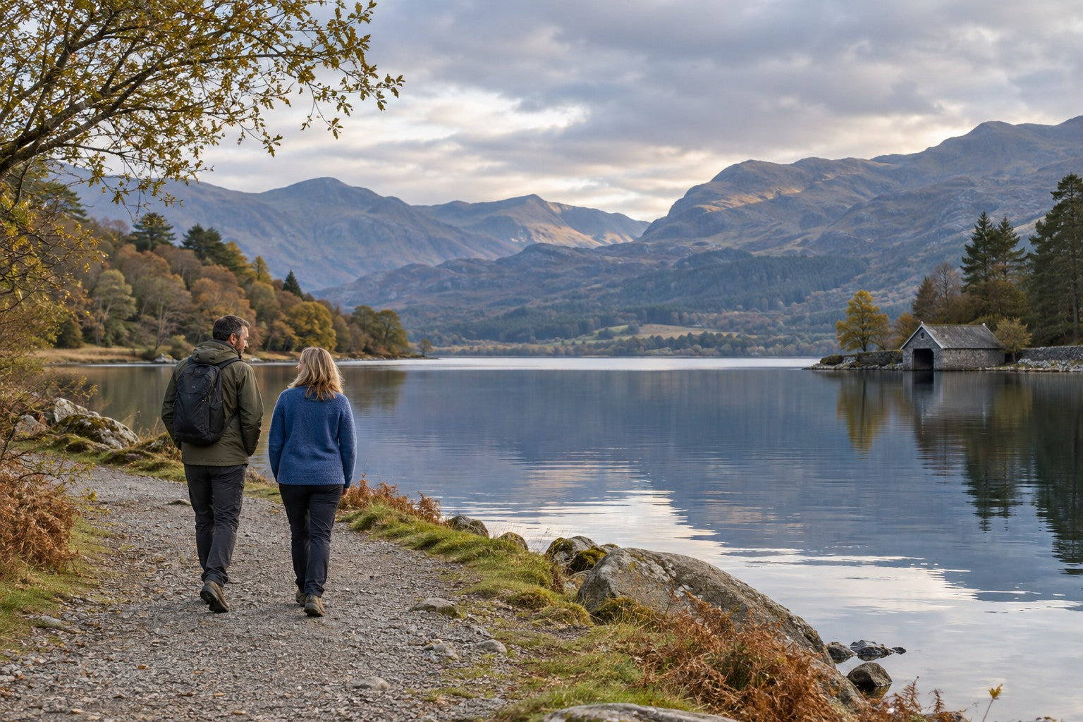 Photograph of two adults walking beside an unnamed mountain lake, with the people included in the wider view.
