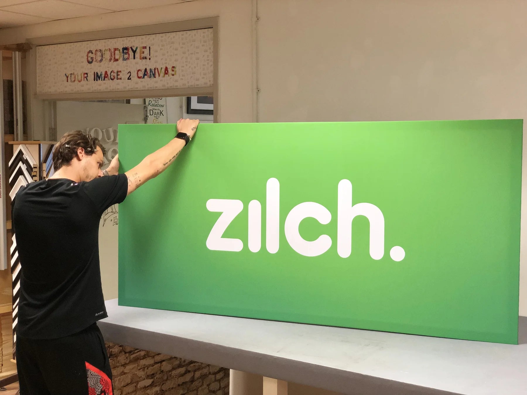 Printmaker finishing a large green branded display panel