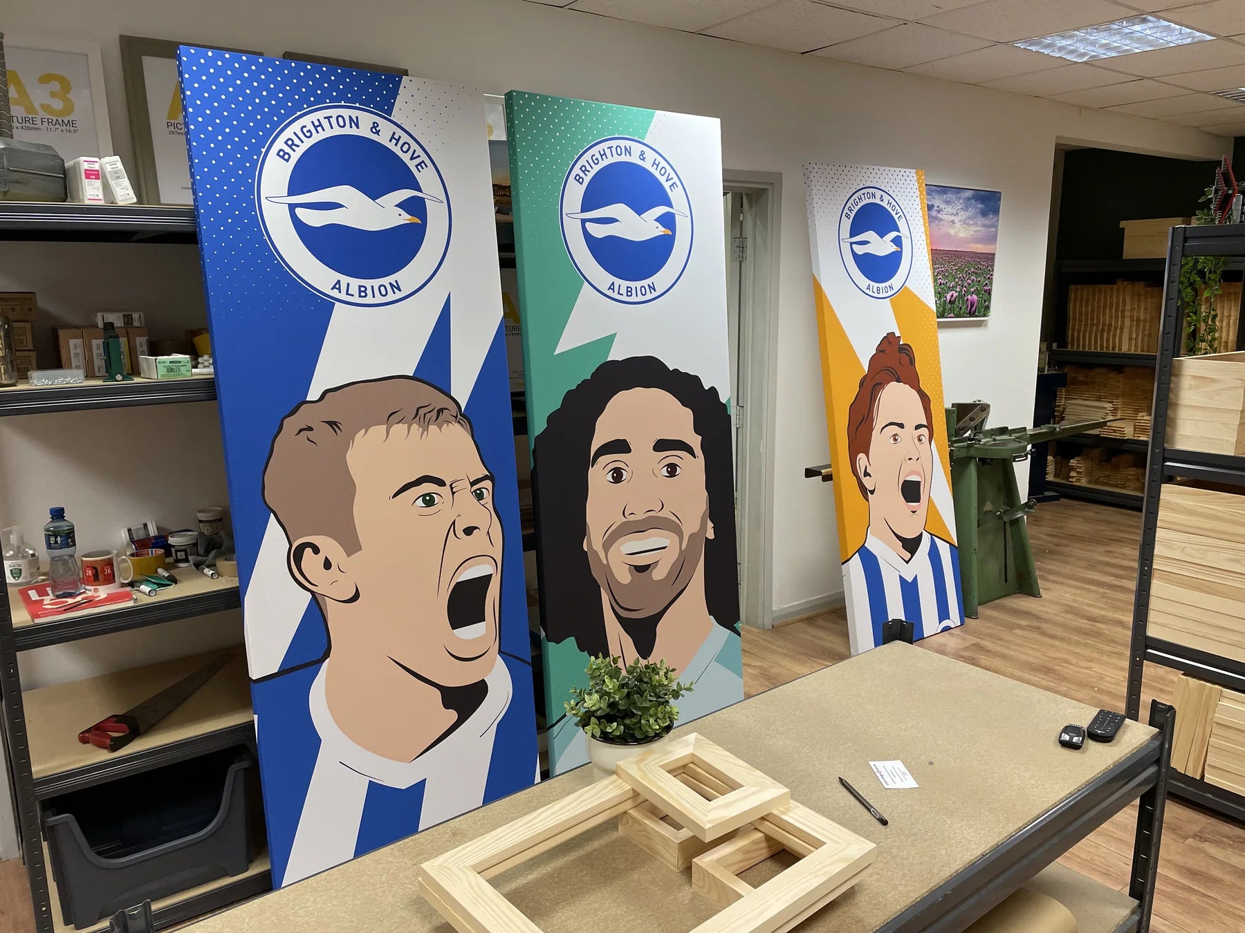 Three illustrated football display panels being checked in the workshop