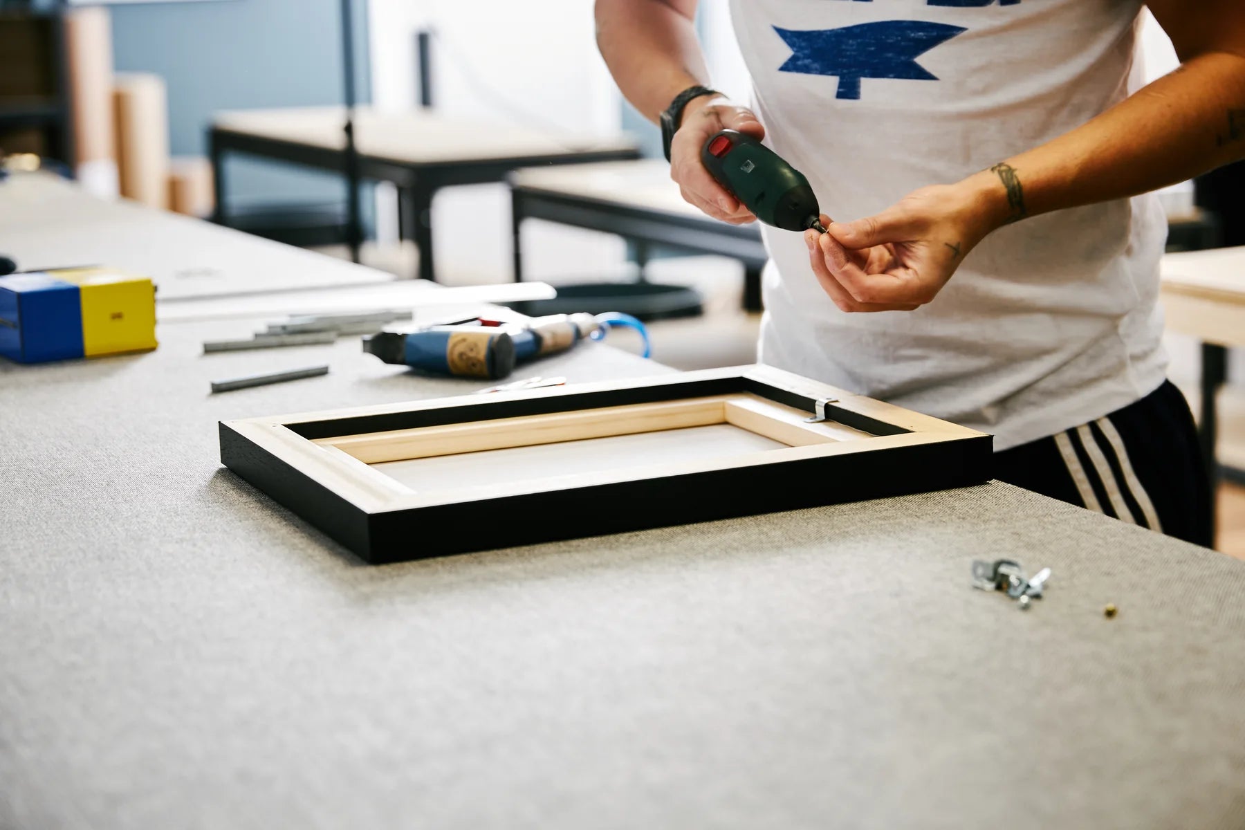 A printmaker fitting hanging hardware to the back of a finished frame