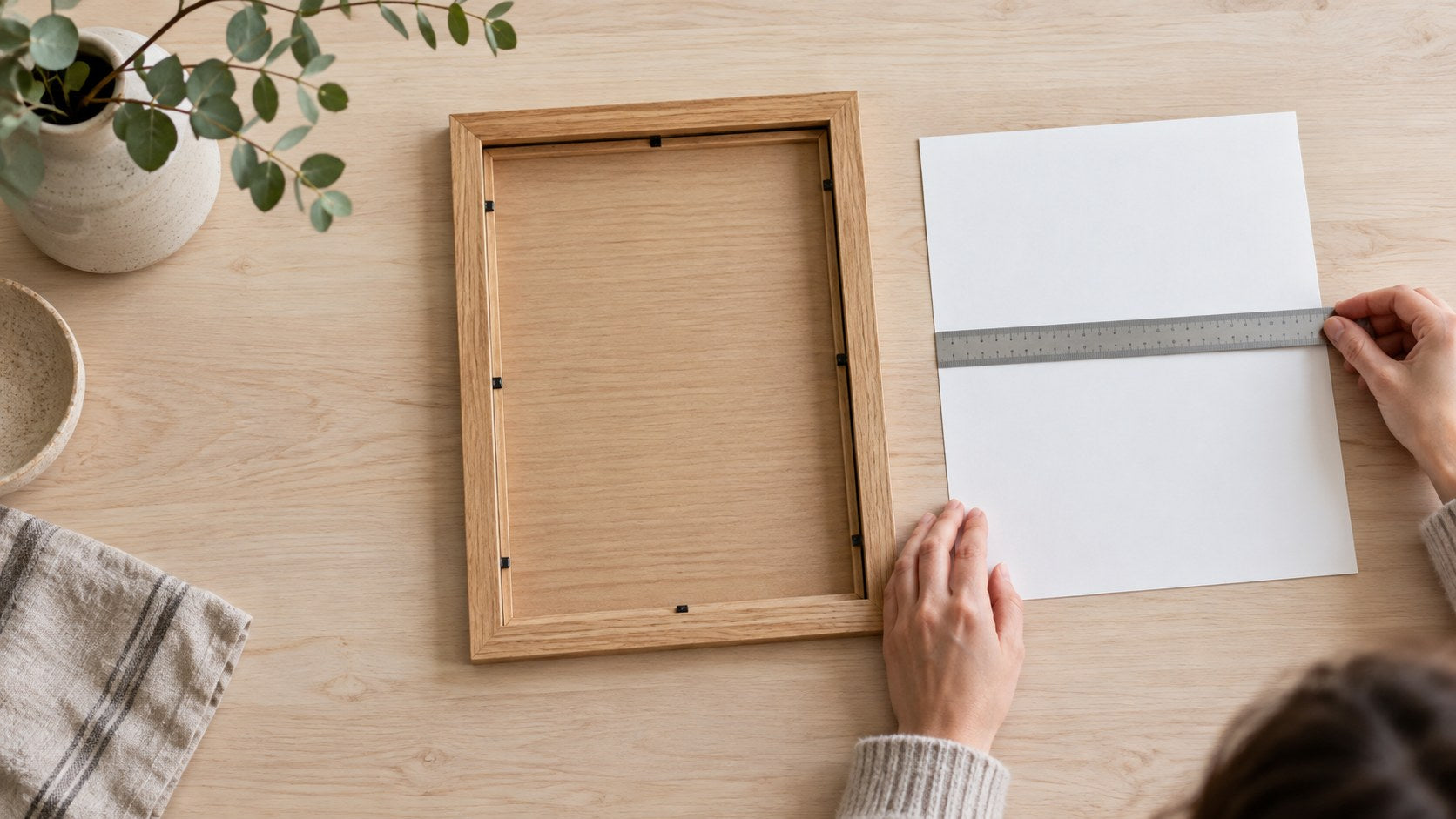 An empty picture frame beside its removed paper insert, with a ruler laid across the insert’s width.