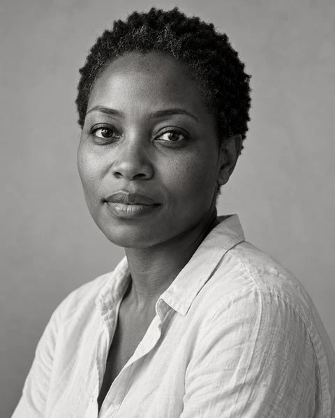 An expressive monochrome portrait of an adult woman with short natural hair, a plain shirt and a steady gaze.