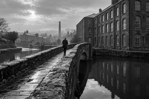 An imagined northern working-town scene with a brick mill beside a canal and one person walking across a footbridge.