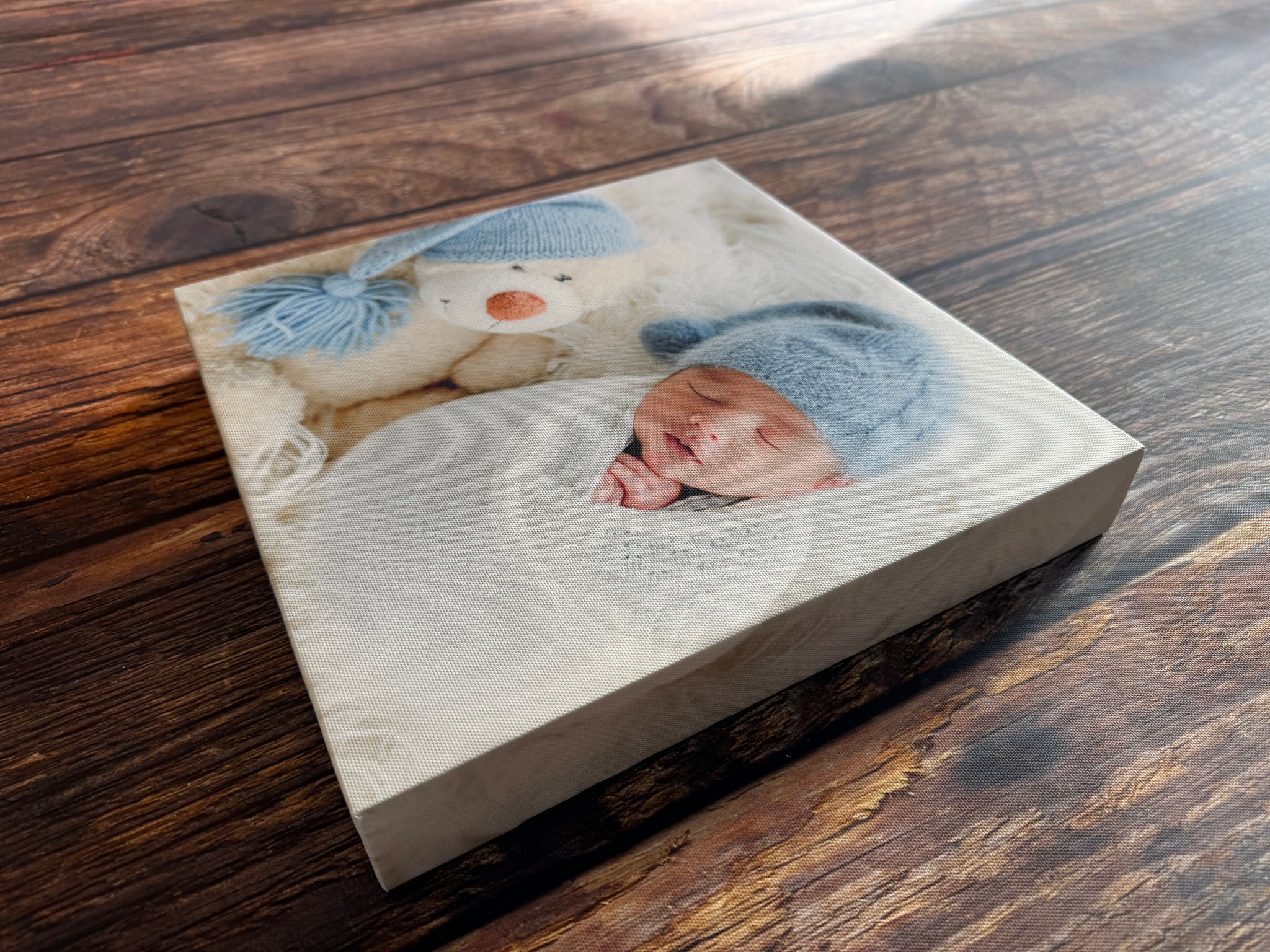 Newborn photograph on a stretched canvas, showing the depth and wrapped corners on a wooden table.