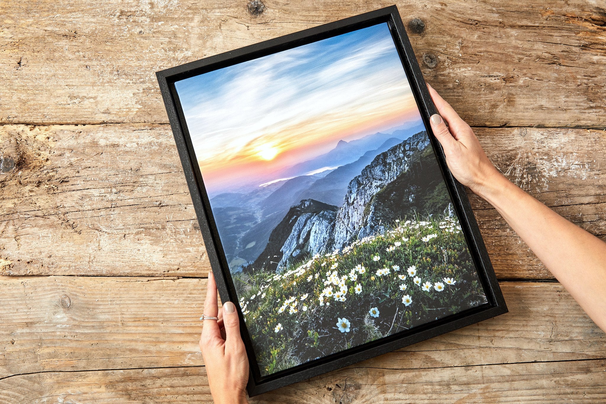 Hands holding a framed mountain landscape print