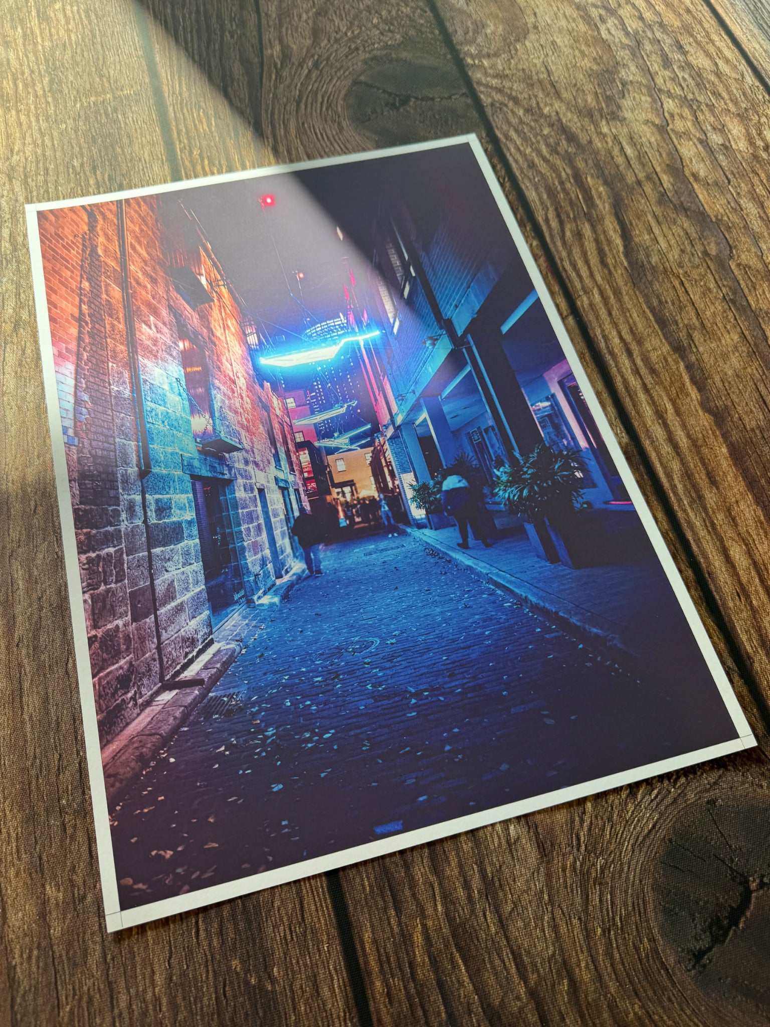 A colourful neon street poster print laid on a wooden table.