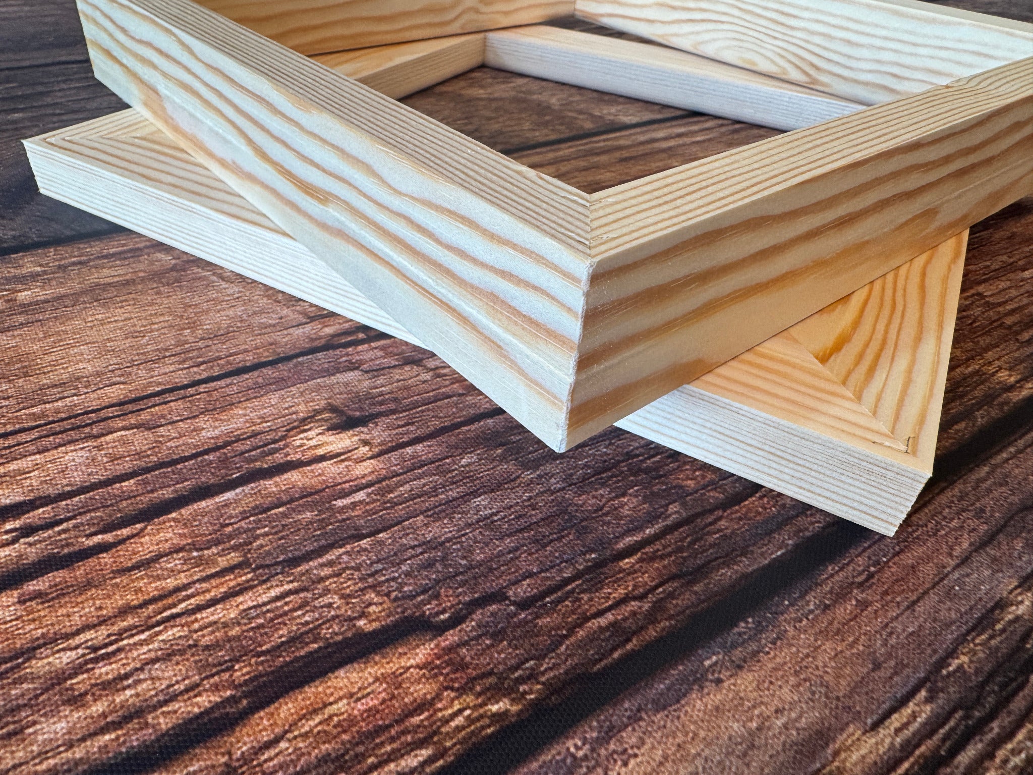 Stacked pine canvas stretcher frames showing the timber grain and mitred corners.