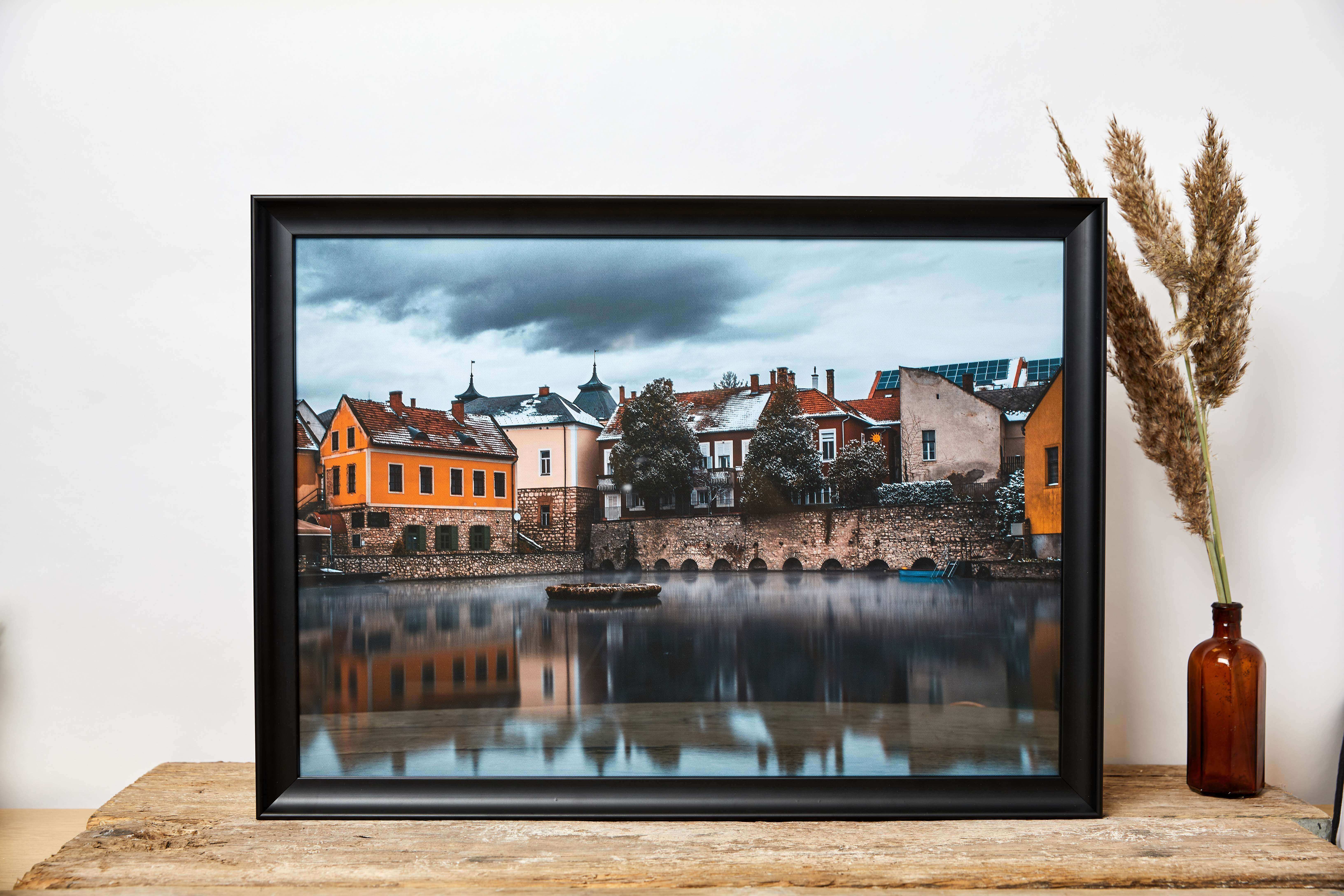 A beautiful autumn scenery canvas print finished with a classic black frame displayed on a wooden desk with free delivery uk