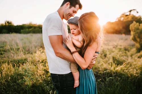  A family photograph of husband and wife stood in a field holding their baby with a sunset background would look great printed onto a good quality canvas 